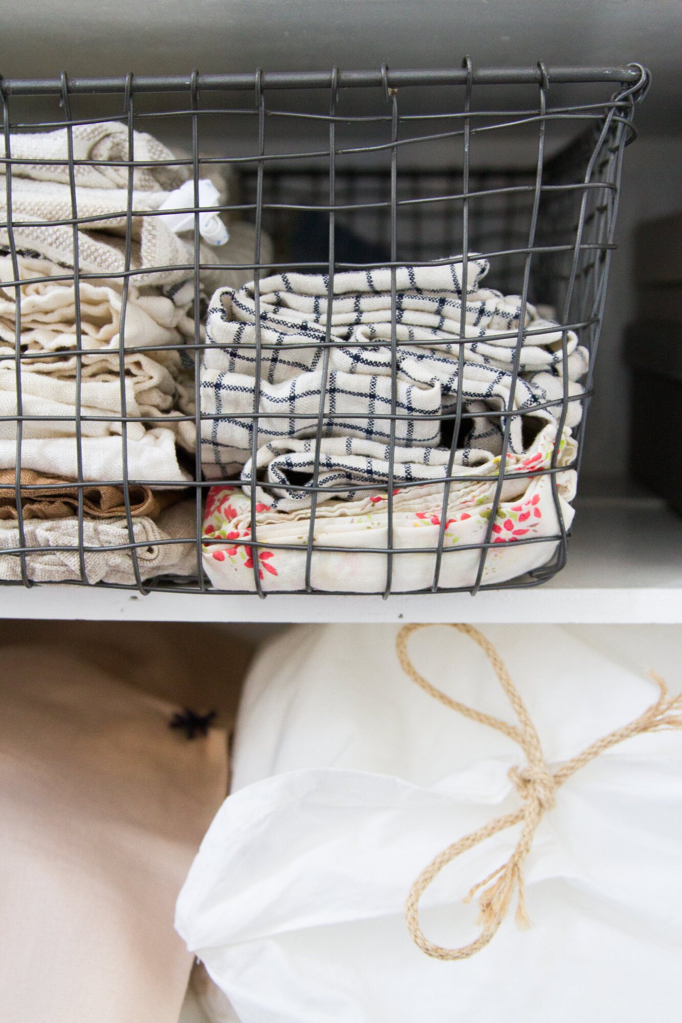 a wire basket filled with dishtowels and cloth napkins.