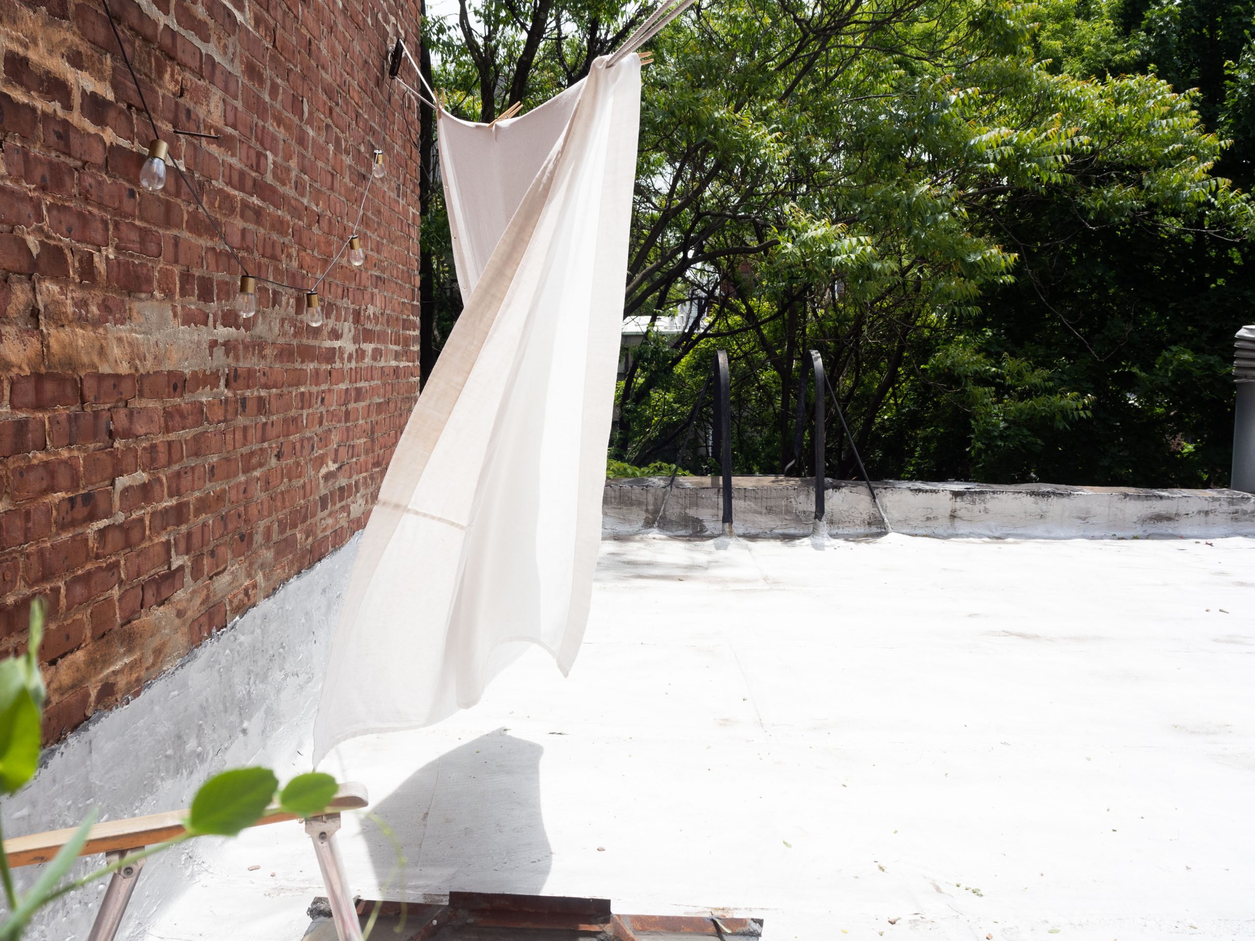 white linen shower curtain hanging on a laundry line
